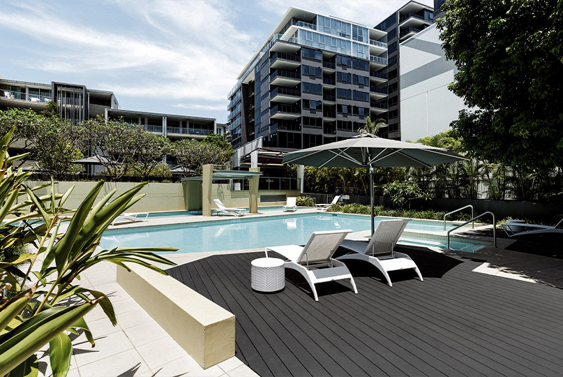 grey composite decking by pool with lounge chairs
