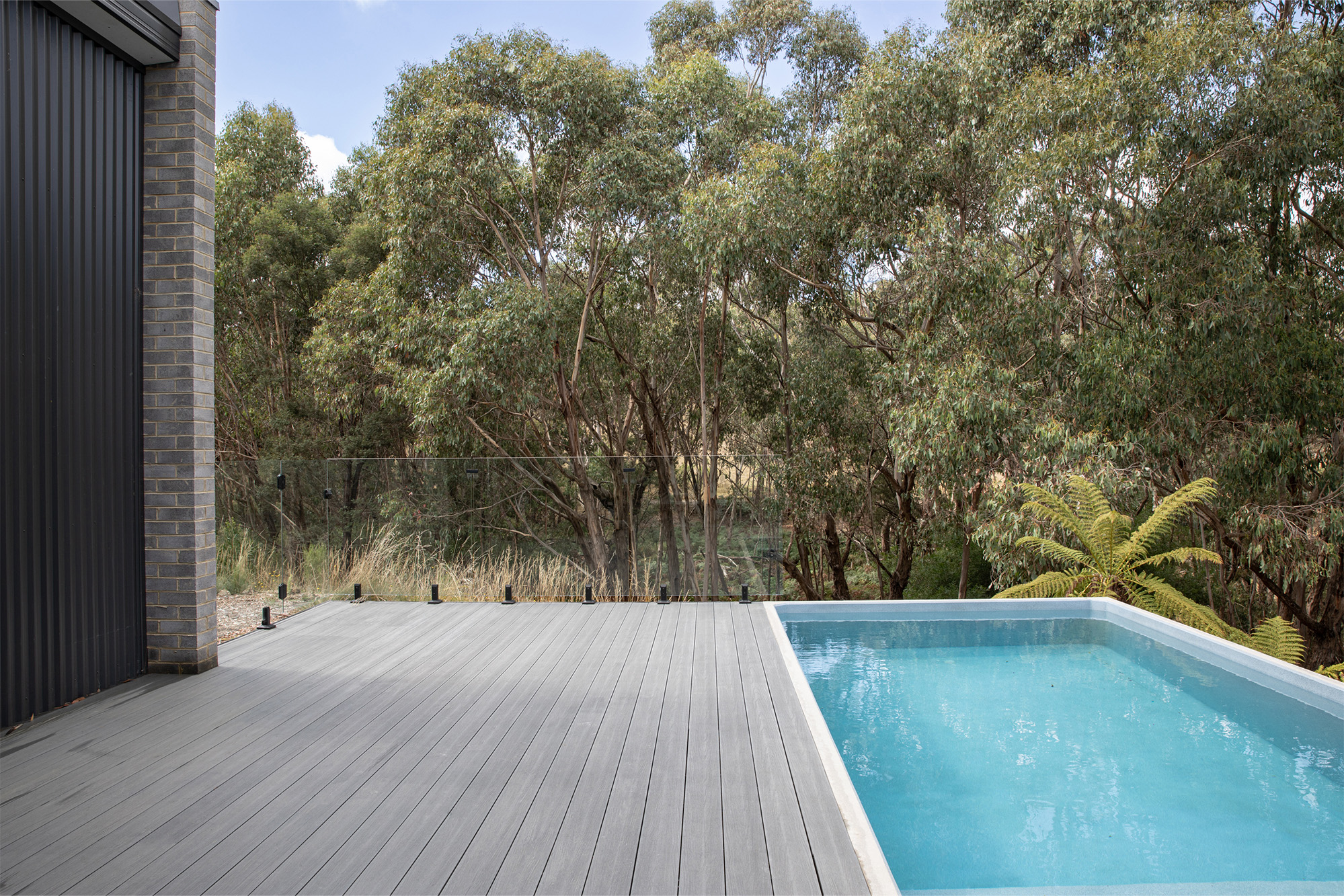 A deck with a swimming pool and trees.