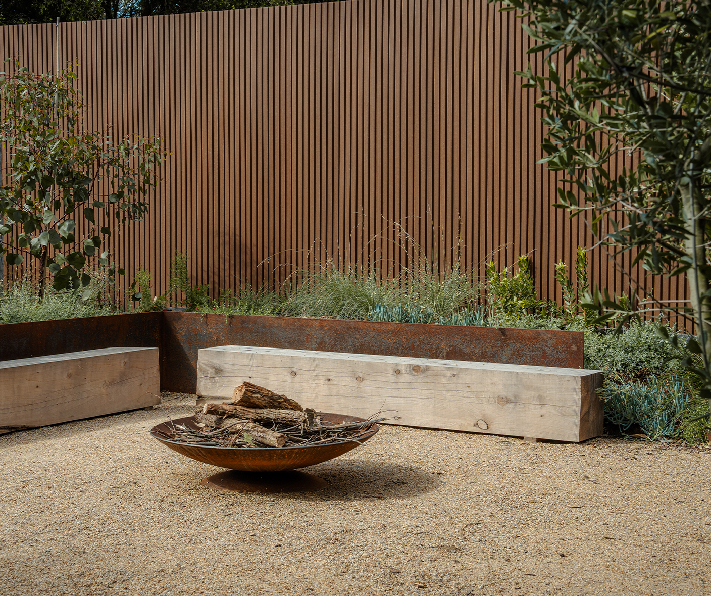 composite cladding fence with fire pit, bench seating and shrubbery
