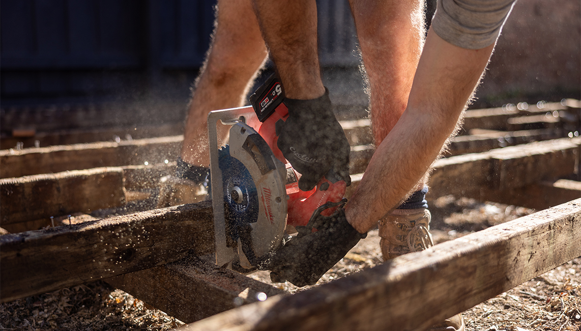 A person using a circular saw on wood.