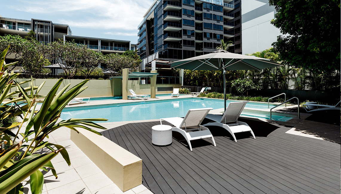 A swimming pool with lounge chairs and umbrellas.